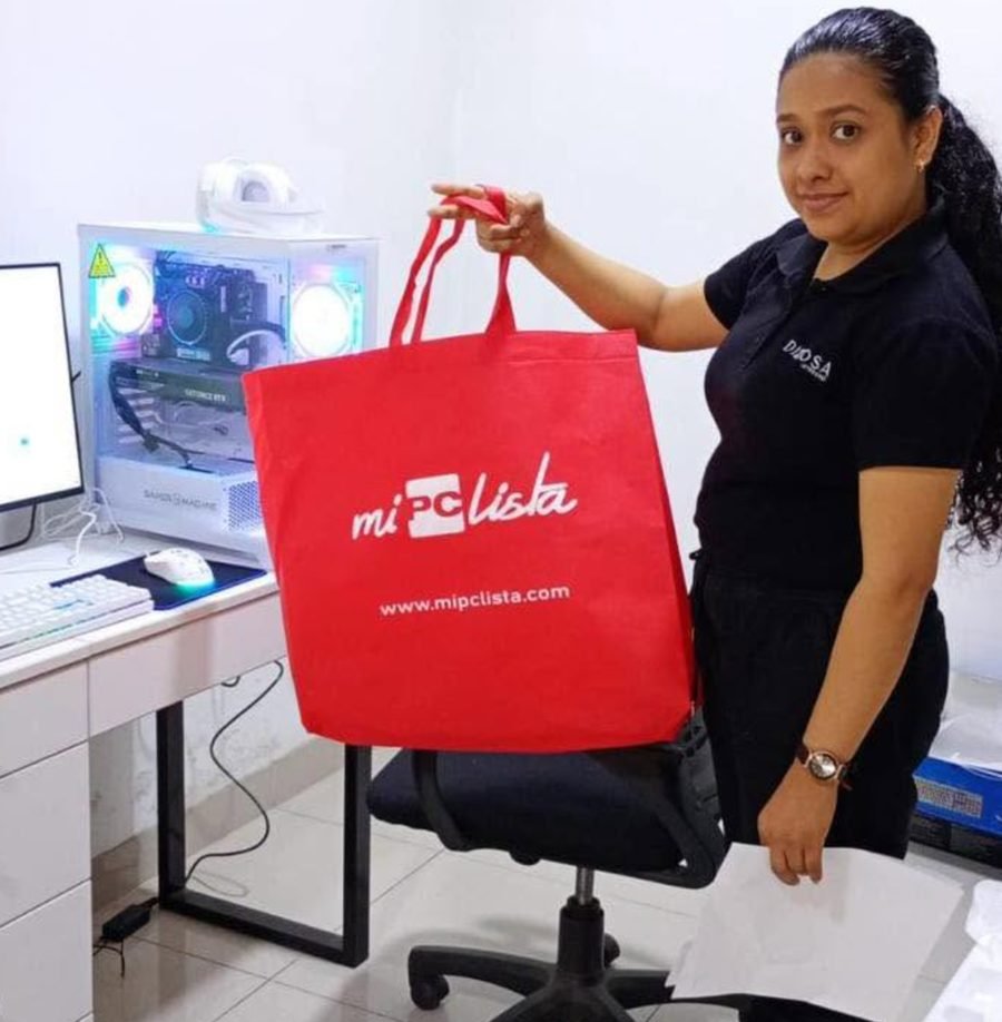 Clienta con la bolsa de su compra junto a su PC gamer blanca instalada
